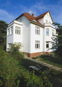 een wit huis met een rood dak bij Villa Daheim - FeWo 04 in Kolpinsee