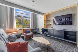 a living room with a large television and a couch at MTN House By Basecamp in Canmore