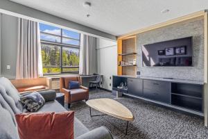 ein Wohnzimmer mit einem großen TV und einem Sofa in der Unterkunft MTN House By Basecamp in Canmore