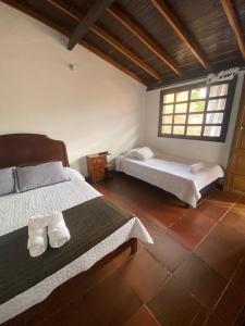 Un dormitorio con dos camas y una ventana. en Casa Naturhola, en Villa de Leyva