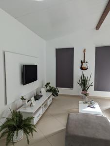 a white living room with a tv and a couch at Finca Pedra Molar in Órgãos
