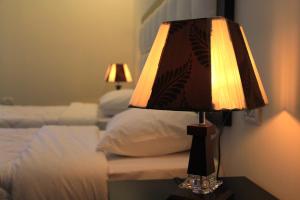 eine Lampe auf einem Tisch neben einem Bett in der Unterkunft Abu Mazen Hotel in Khirbat an Naşārá