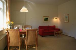ein Wohnzimmer mit einem Tisch und einem roten Sofa in der Unterkunft Villa Daheim - FeWo 07 in Ostseebad Kölpinsee