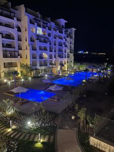 un hôtel avec piscines bleues et parasols la nuit dans l'établissement AlDau Heights Apartments, à Hurghada