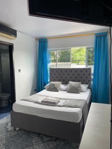 a bedroom with a large bed with blue curtains at HospedajeLR in Barrancabermeja