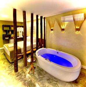 a bathroom with a large tub in a room with a bed at Pousada Noah Noah in São Miguel dos Milagres