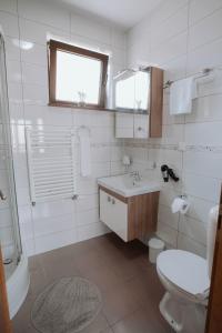 a white bathroom with a sink and a toilet at Apartments Peric Županja in Županja