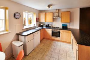 uma cozinha com armários de madeira e bancadas pretas em Spacious 4-bed, 3-bath home perfect for large groups em Tamworth