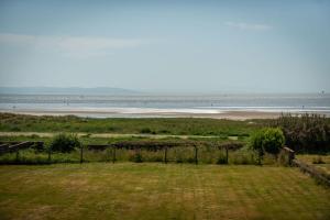 a view of a beach with a grass field and the ocean at Sea View Luxury Beach House in Crosby