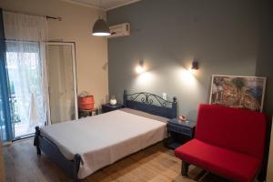 een slaapkamer met een bed en een rode stoel bij DIMITRA APARTMENTS in Pefki