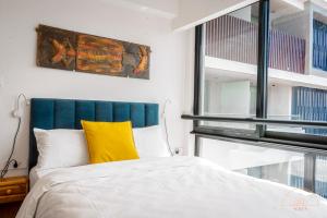 a bedroom with a bed with a yellow pillow at SOLEA - Super central, comfortable and modern apartment in Accra
