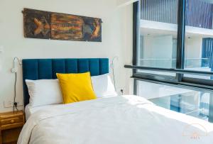 a bedroom with a large bed with a yellow pillow at SOLEA 1 bedroom apartment - Central, comfortable, cozy, balcony, pool, gym in Accra +29 photos