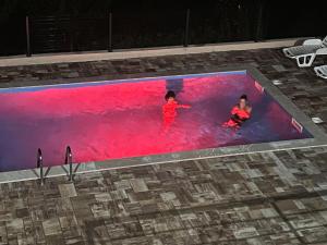 Dos niños están nadando en una piscina de agua roja en Villa Hani, en Sarajevo