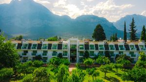 a large white building with mountains in the background at OMORFİ GARDEN RESORT in Dedeköy