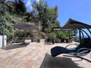 une terrasse avec une chaise et un parasol dans l'établissement THE WHITE HOUSE BEAUSOLEIL- Monaco Border, à Beausoleil