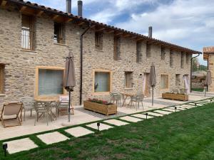 a patio with chairs and tables in front of a building at CAL GALL rural Cerdanya in Bellver de Cerdanya