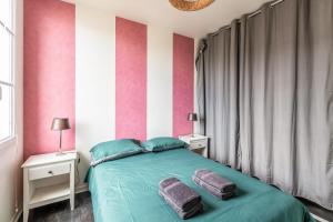 a bedroom with a green bed with pink and white stripes at Flat with terrace near Disneyland Paris - Welkeys in Bailly-Romainvilliers