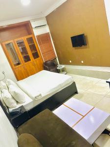 Posh Hotel and Suites Ikeja في إيكيجا: غرفة نوم بسريرين وتلفزيون بشاشة مسطحة
