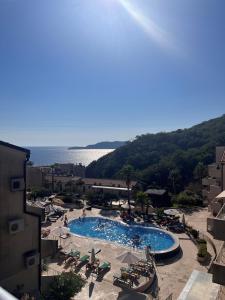 a large swimming pool with lounge chairs and the ocean at Charming apartment near beach in Sveti Stefan