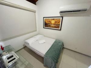 a small room with a bed and a picture on the wall at Flat Duplex - Muro Alto Malawí in Porto De Galinhas