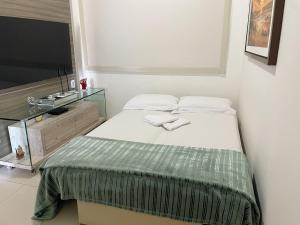 a small bedroom with a bed and a television at Flat Duplex - Muro Alto Malawí in Porto De Galinhas