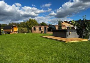 un gran patio con una casa y una terraza de madera en Tirolian Lodge North, Whirlpool, Sauna, Lagerfeuer, en Bundorf