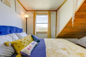 a bedroom with a bed with a blue headboard and a window at Historic Alpine Cabin with Scenic Mount Sopris View in Glenwood Springs