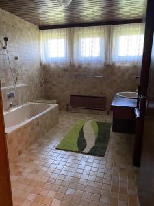 a bathroom with a tub and a green rug at Gemütliches Haus in Seewalchen am Attersee in Seewalchen