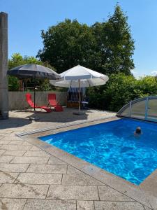 a swimming pool with two umbrellas and two chairs at Gemütliches Haus in Seewalchen am Attersee in Seewalchen