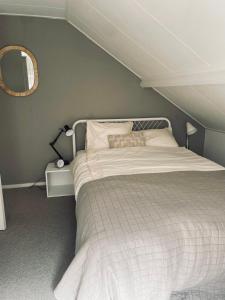 een slaapkamer met een wit bed en een spiegel bij Tiny beachhouse - free parking in Noordwijk
