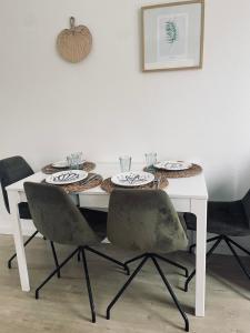 een witte tafel met twee stoelen en een tafel met borden bij Tiny beachhouse - free parking in Noordwijk
