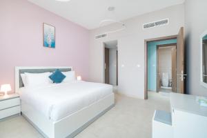 a white bedroom with a white bed and a bathroom at Trinity Holiday Homes - Spacious Modern Living 2BR Unique Apartment in Dubai