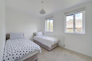 a bedroom with two beds and two windows at Private house seconds from Portobello Road in London