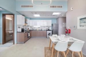 a kitchen with a white table and white chairs at Trinity Holiday Homes - Spacious Modern Living 2BR Unique Apartment in Dubai