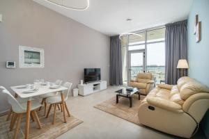 uma sala de estar com um sofá e uma mesa e uma sala de jantar em Trinity Holiday Homes - Spacious Modern Living 2BR Unique Apartment em Dubai