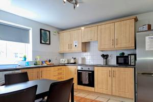 a kitchen with wooden cabinets and a table with chairs at Kings Lodge One Bed Apartment in Belfast