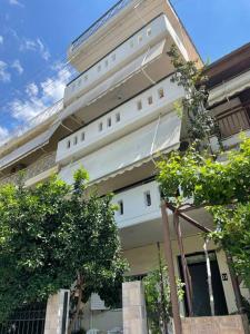 un bâtiment blanc avec des arbres devant lui dans l'établissement George Apartment, à Lamía