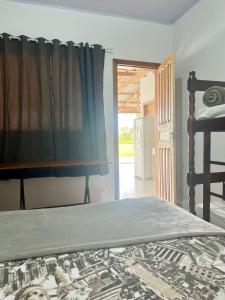 a bedroom with a bed and a window with a curtain at Recanto Monte Trigo in São Francisco do Sul