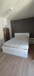 białe łóżko w pokoju z drewnianą podłogą w obiekcie Chez Manolo & Jolyne w mieście Givet
