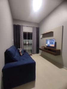 Dunas residence casa 15- Lençois Maranhense في سانتو أمارو: غرفة معيشة مع أريكة زرقاء وتلفزيون بشاشة مسطحة
