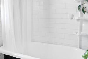 uma casa de banho com uma cortina de chuveiro branca e uma banheira em Rare find in Kitsilano! em Vancouver