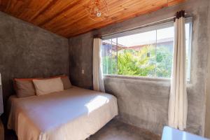 a bedroom with a bed and a window at Vita Chalés, na avenida central in Alto Paraíso de Goiás