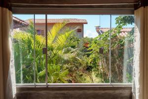 an open window with a view of a garden at Vita Chalés, na avenida central in Alto Paraíso de Goiás