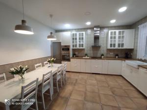 cocina grande con armarios blancos, mesa y sillas en Casa La Alquería en Chiclana de la Frontera