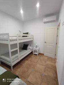 a room with a white bunk bed and a tiled floor at Casa La Alquería in Chiclana de la Frontera
