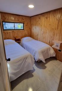 two beds in a room with wooden walls at RAMAL LODGE CONSTITUCION in Constitución