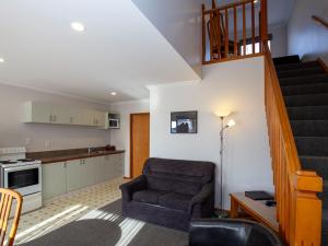 sala de estar con silla y escalera en ASURE Chelsea Gateway Motor Lodge, en Westport