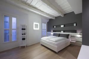 ein weißes Schlafzimmer mit einem weißen Bett und einigen Fenstern in der Unterkunft Como Luxury Rooms in Como