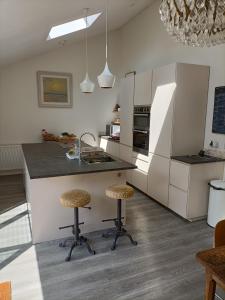 cocina con fregadero y 2 taburetes en Cybil's Retreat - Renovated 2 bedroom house with enclosed garden, en Uppingham