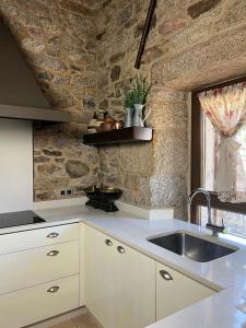 a kitchen with a sink and a stone wall at A Eira da Laxe in Cerdedo